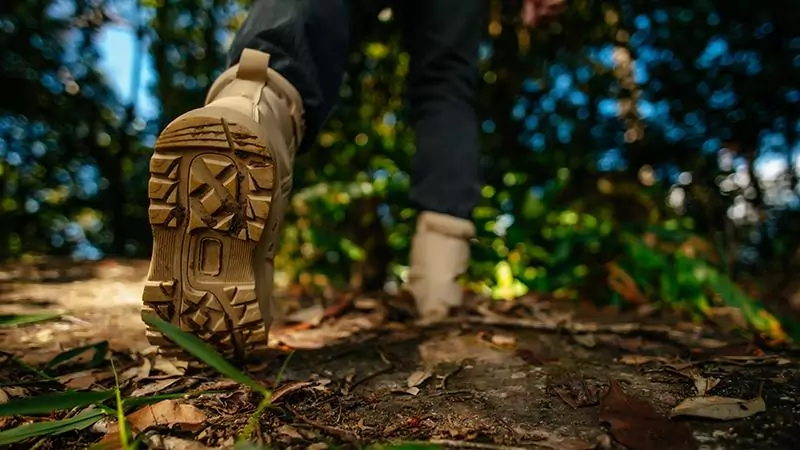 feche os sapatos do caminhante andando na trilha da floresta com espaco de copia da luz solar